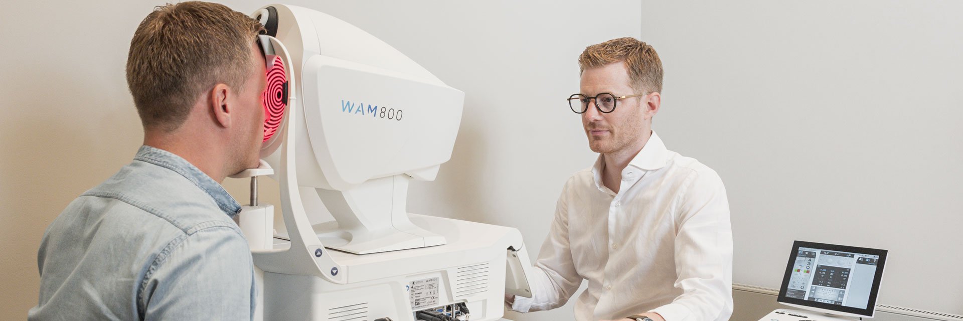 Ein Optiker vermisst die Augen eines Kunden mit einem Wellenfrontmessgerät, Keratograph.