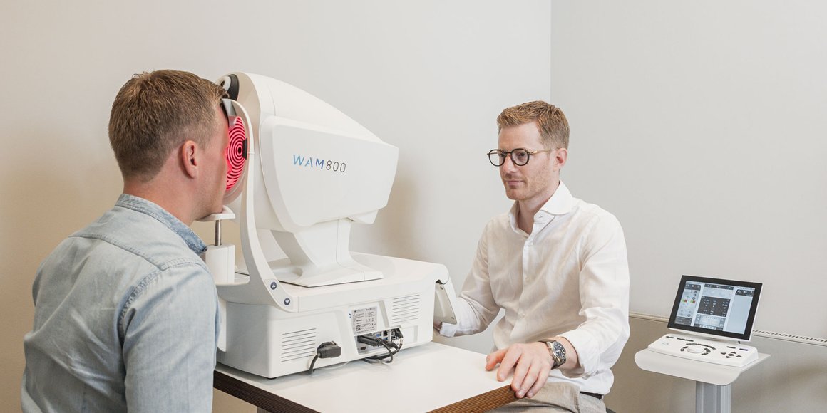 Ein Optiker vermisst die Augen eines Kunden mit einem Wellenfrontmessgerät, Keratograph.