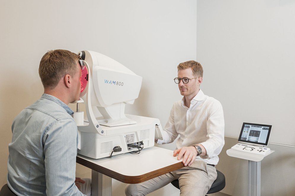 Ein Optiker vermisst die Augen eines Kunden mit einem Wellenfrontmessgerät, Keratograph.