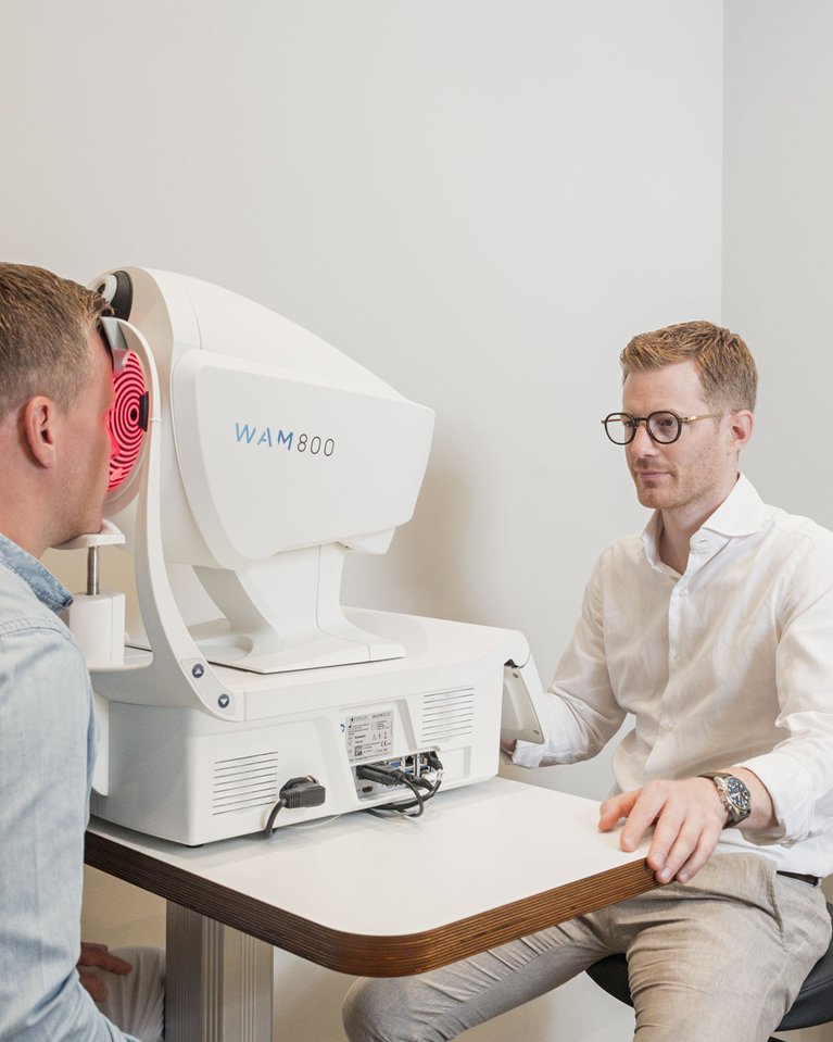 Ein Optiker vermisst die Augen eines Kunden mit einem Wellenfrontmessgerät, Keratograph.