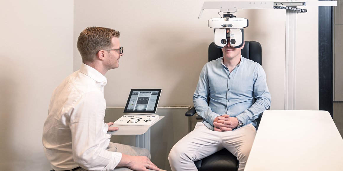 Augenoptiker und Kunde bei einem modernen, hochwertigen Sehtest. Vermessen mit der neuesten Sehtest-Technologie