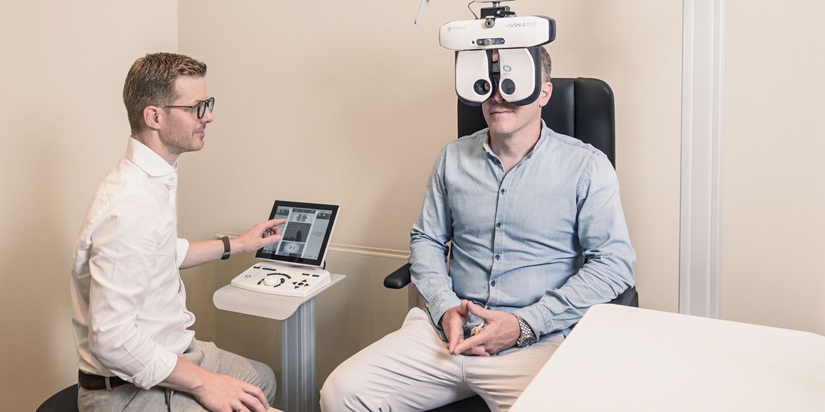 Kunde lässt seine Sehstärke mit einem modernen Augenmessgerät bei einem Optiker überprüfen.