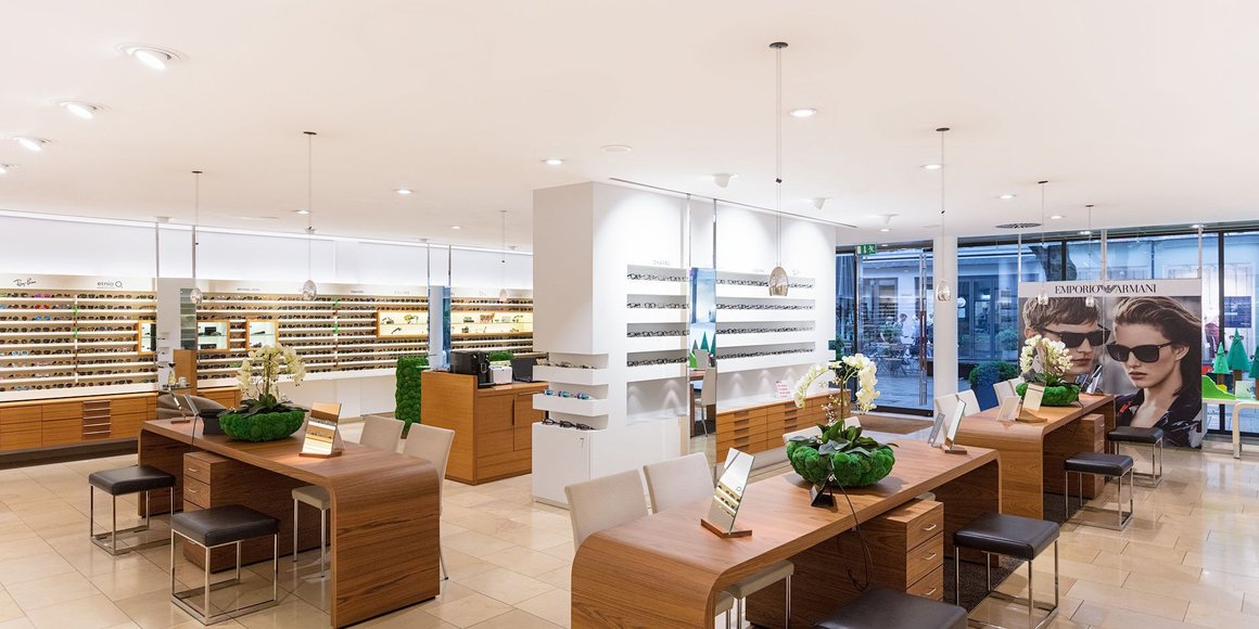 Helles Optikgeschäft mit Beratungstischen und zahlreichen Brillenregalen Emporio Armani