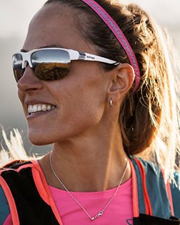 Smiling athlete wearing sunglasses, brand text evil eye true sport eyewear